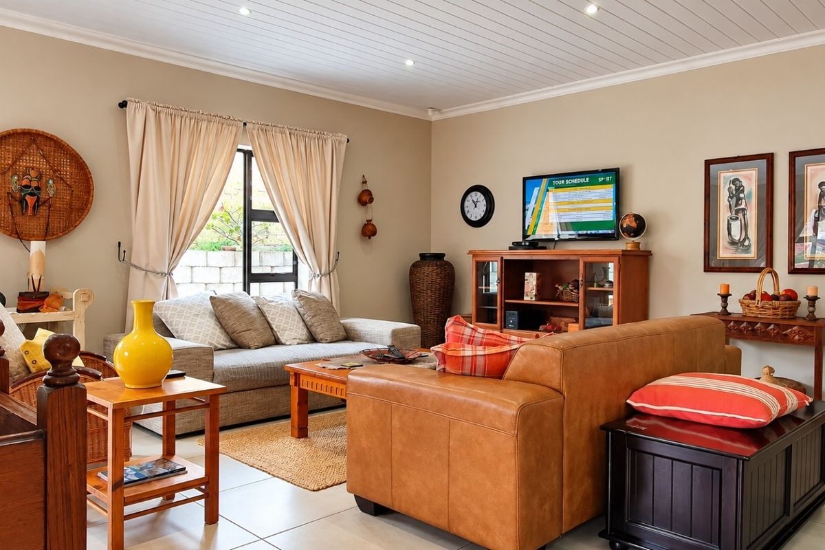 A comfortable living room featuring tiled flooring, recessed downlighting, and a classic tongue and groove ceiling, creating a warm and inviting atmosphere.