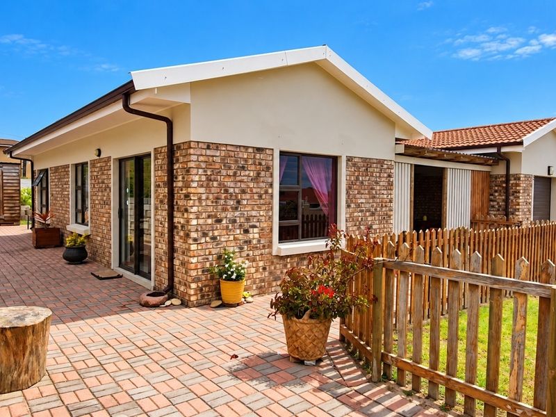 A well-maintained rear exterior view featuring a brick facade, paved patio area, and timber picket fencing, providing a clean and inviting outdoor space.