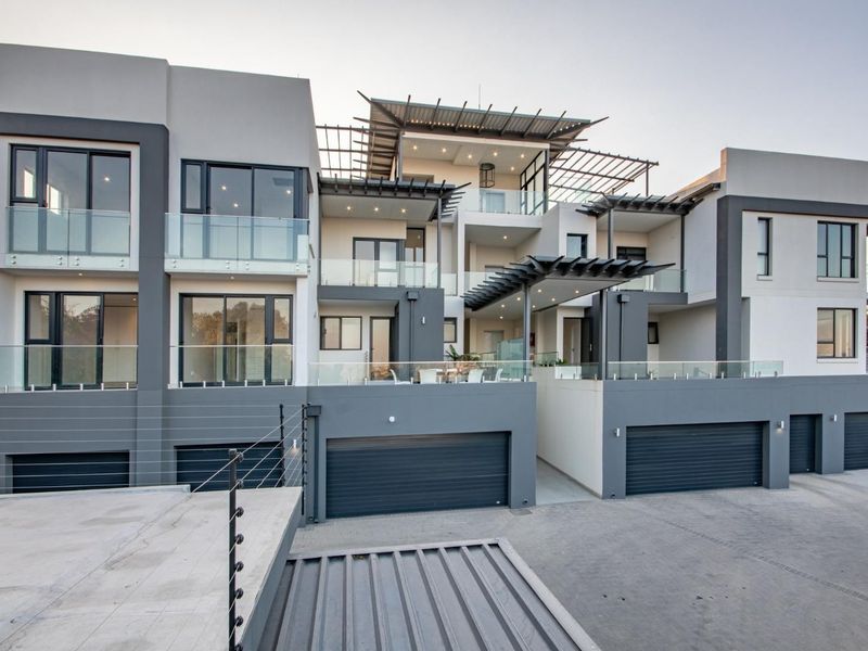 Modern multi-level apartment complex featuring contemporary architectural design, glass balustrades, integrated pergolas, and multiple automated garage access points.