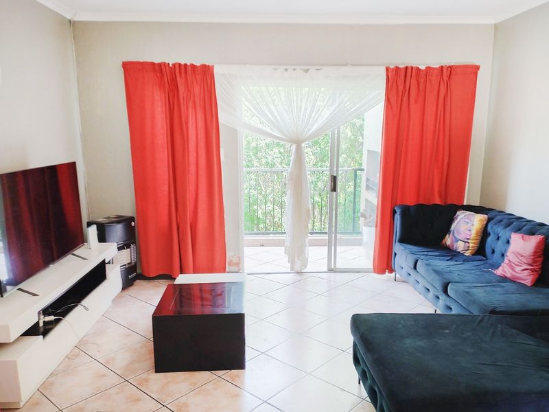 A living room featuring tiled flooring and a sliding glass door leading to a balcony, providing natural light and access to outdoor space.