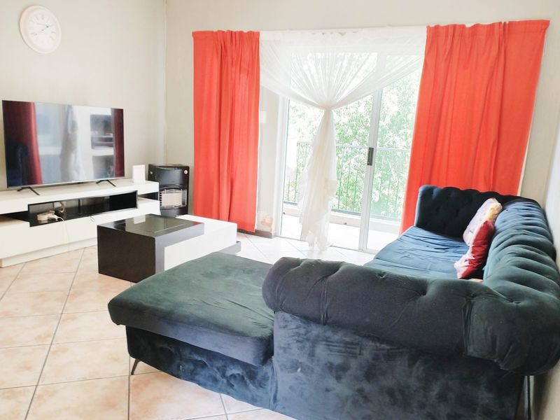 A living room featuring ceramic floor tiles and a sliding glass door providing access to a balcony.