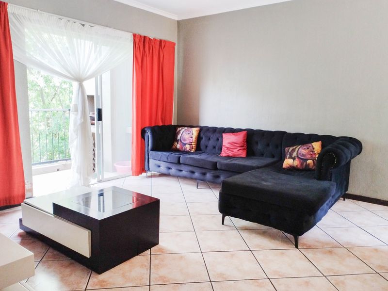 A living room featuring tiled flooring and a sliding glass door providing direct access to an outdoor balcony area.