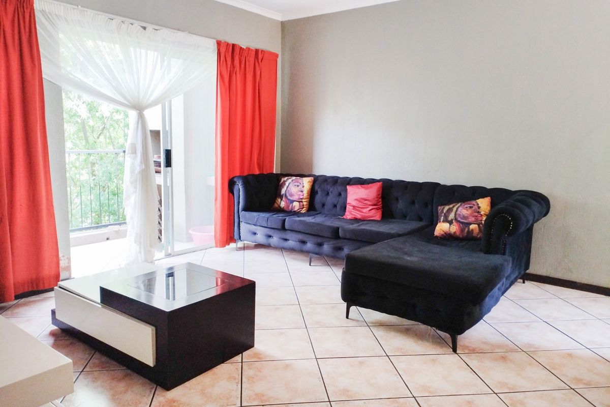 A living room featuring tiled flooring and a sliding glass door providing direct access to an outdoor balcony area.