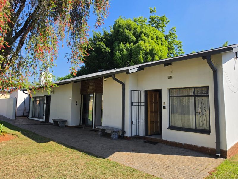 Rear exterior view of the guest house featuring a paved patio area, security gates, and direct access to multiple units.
