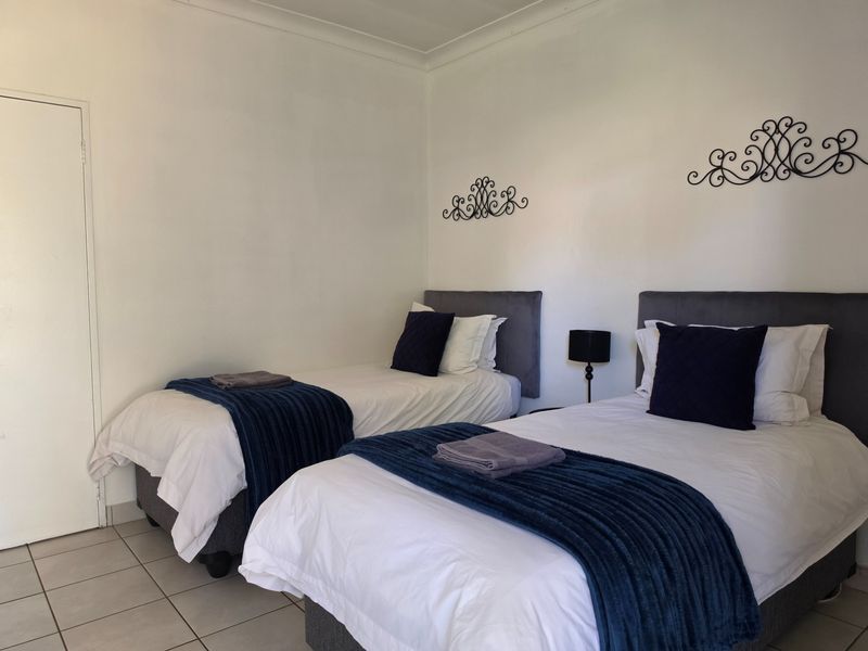 A clean and well-maintained bedroom featuring tiled flooring and coved ceilings, currently configured with twin beds.