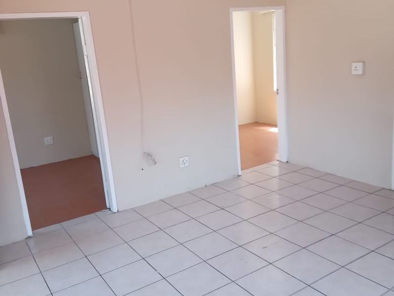 An empty living room featuring ceramic floor tiles, coved ceiling cornices, and multiple doorways leading to adjacent rooms.