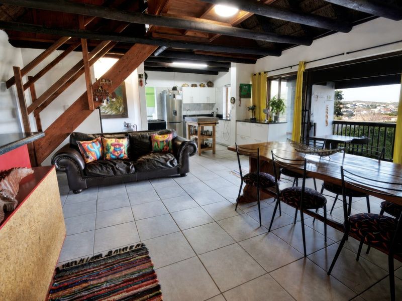 Spacious open-plan living and dining area featuring exposed timber beams, tiled flooring, and direct access to a balcony through large sliding glass doors.