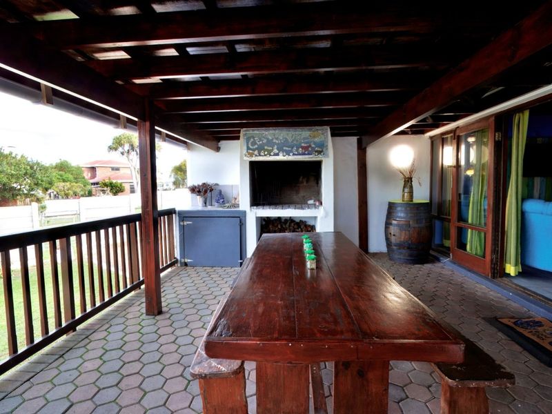 Covered outdoor patio featuring a built-in braai, timber pergola roof, and paved flooring, ideal for alfresco dining and entertaining.