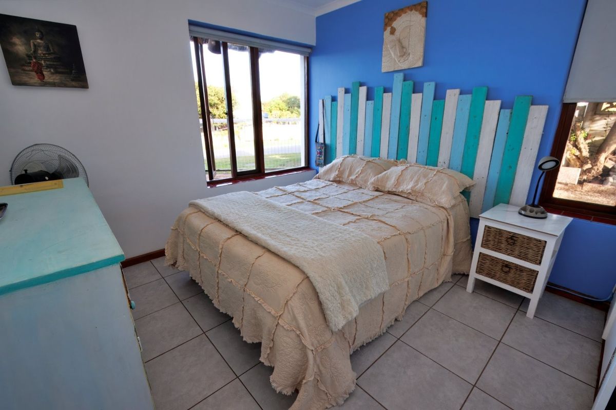 A bedroom featuring tiled flooring and aluminium window frames, with a bright blue accent wall.