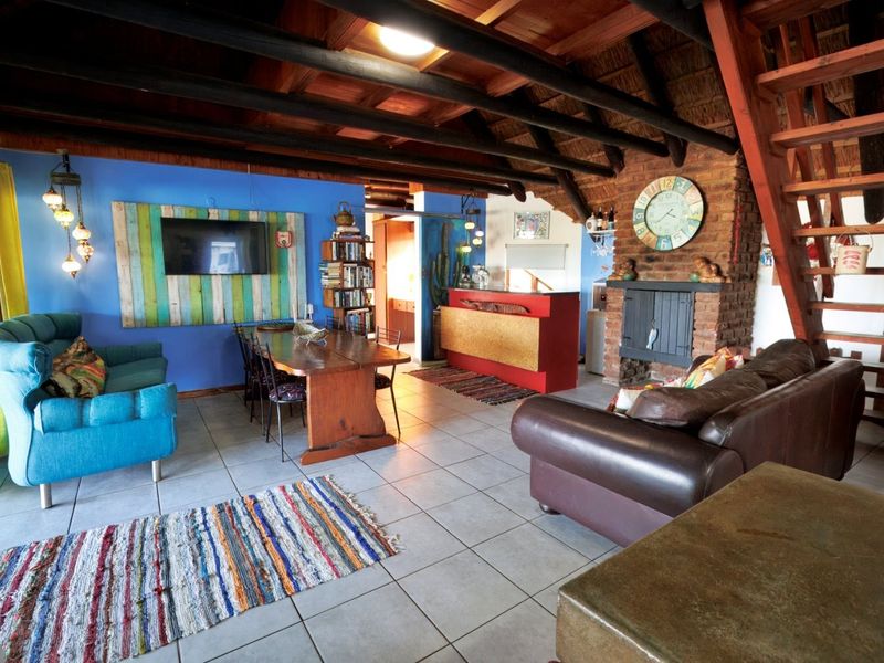 Spacious open-plan living area featuring exposed timber beams, a brick fireplace, and a built-in bar, creating a rustic and inviting atmosphere.