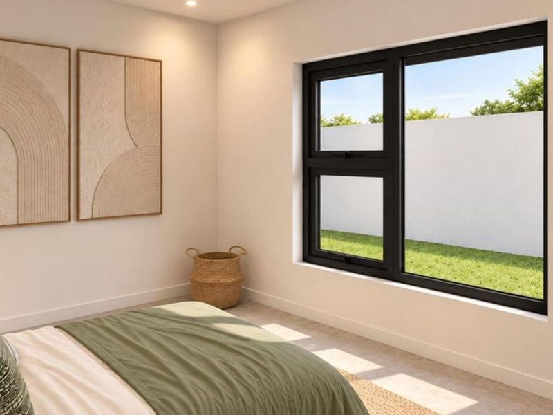 A modern, well-lit bedroom featuring a large black-framed window overlooking a private garden area.