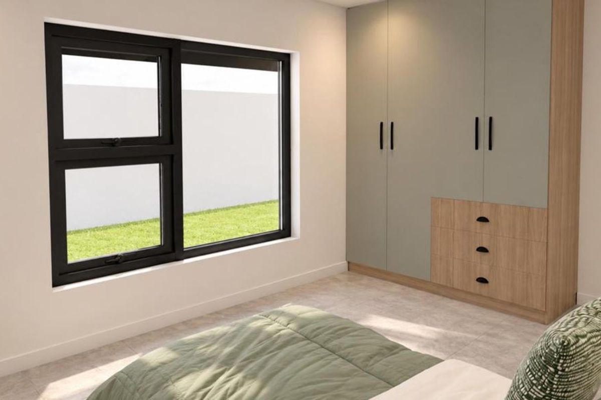 A modern bedroom featuring a built-in wardrobe with a two-tone finish, tiled flooring, and a large aluminium-framed window overlooking the garden.