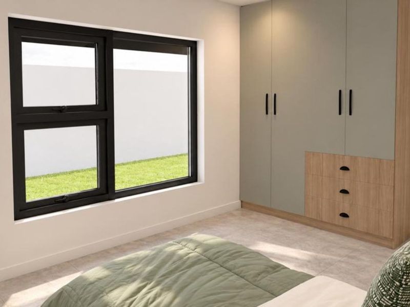A modern bedroom featuring a built-in wardrobe with a two-tone finish, tiled flooring, and a large aluminium-framed window overlooking the garden.