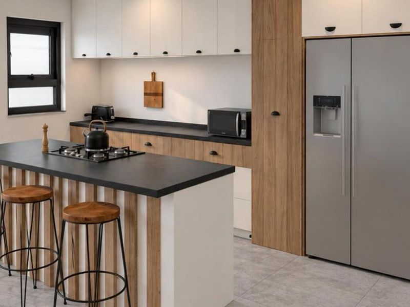 Modern kitchen featuring a central island with a gas hob, sleek two-tone cabinetry, stone countertops, and contemporary tiled flooring.