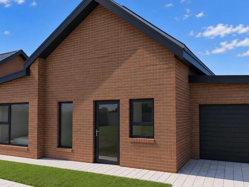 Modern single-story brick house featuring a clean facade, integrated garage, and paved driveway, presenting a contemporary and well-maintained exterior appearance.