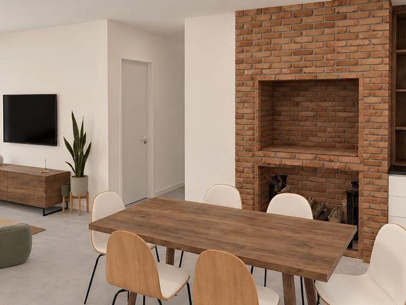 Modern open-plan living and dining area featuring a striking exposed brick fireplace and custom built-in cabinetry with sleek tiled flooring throughout.
