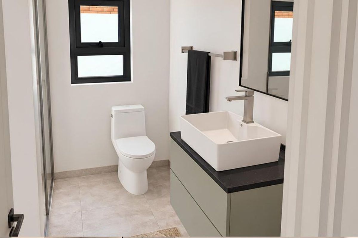 Modern bathroom featuring a sleek vessel sink on a vanity cabinet, a toilet, and a glass-enclosed shower with contemporary finishes.