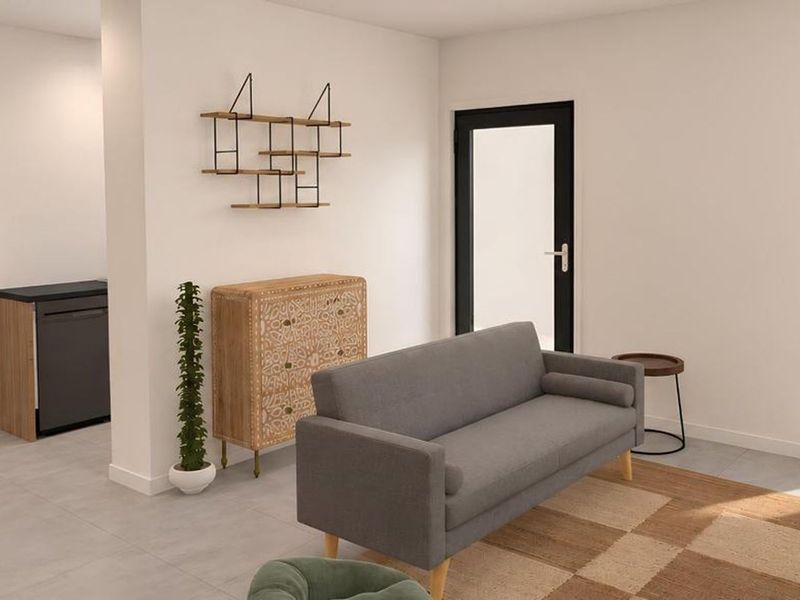 A modern open-plan living area featuring neutral tiled flooring, clean white walls, and contemporary black-framed windows and doors.