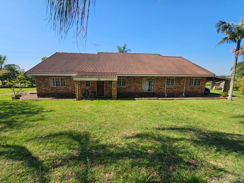 Rear view of a single-story face brick house featuring a tiled roof, covered entrance, and surrounding garden space.