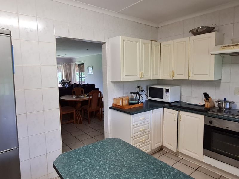 A functional kitchen featuring built-in cabinetry, laminate countertops, an integrated oven, and a hob with an extractor fan, finished with tiled splashbacks.
