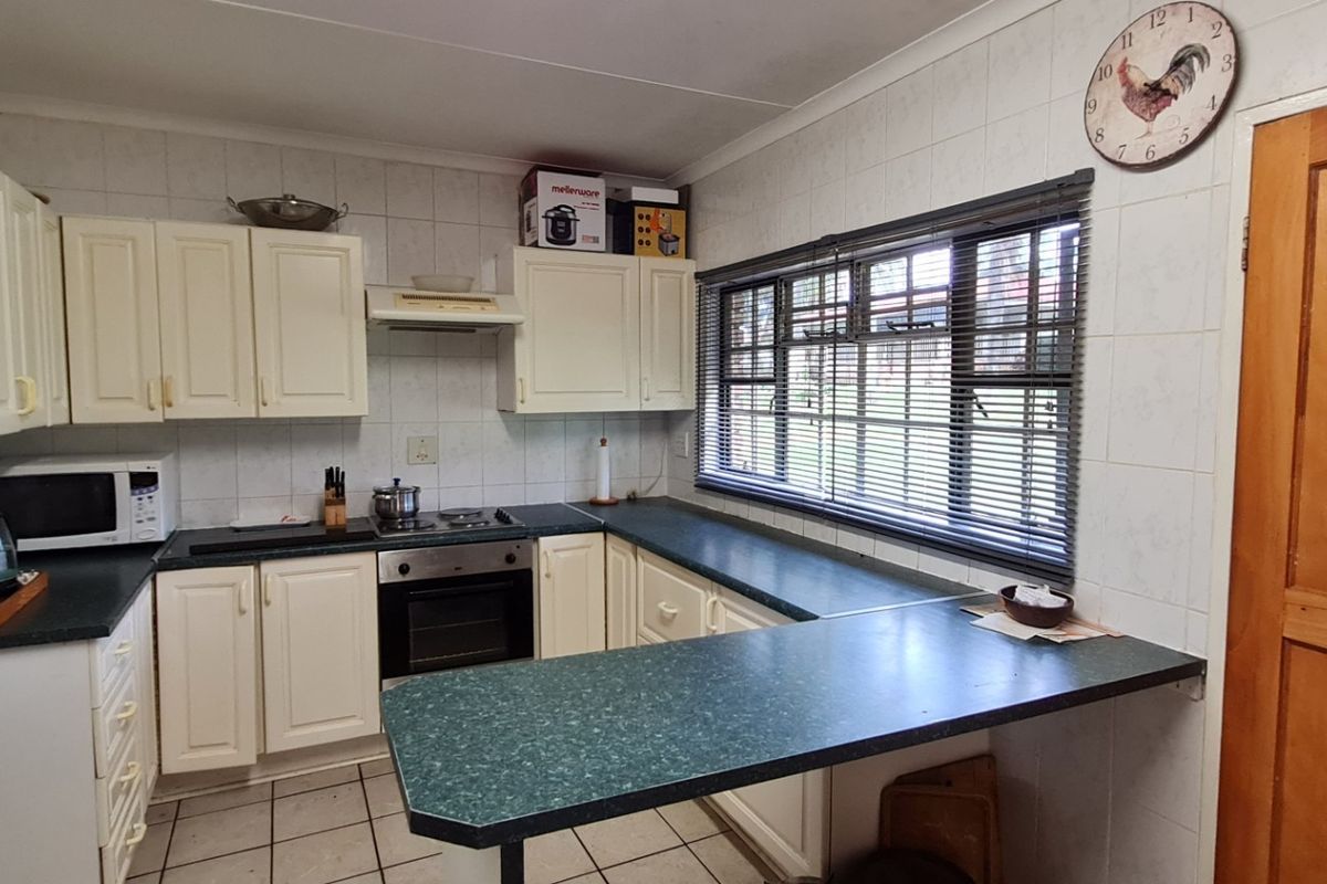 Functional kitchen featuring built-in cabinetry, laminate countertops, integrated oven and hob, tiled backsplash, and tiled flooring with a breakfast nook area.