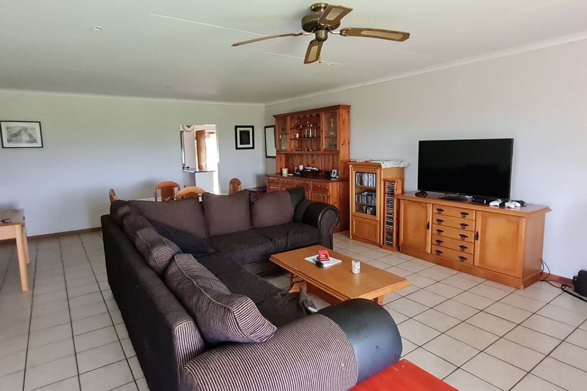 Spacious living room featuring neutral walls, tiled flooring, and a ceiling fan, offering a functional layout with direct access to adjacent living areas.