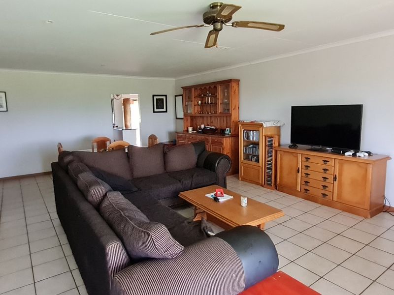 Spacious living room featuring neutral walls, tiled flooring, and a ceiling fan, offering a functional layout with direct access to adjacent living areas.