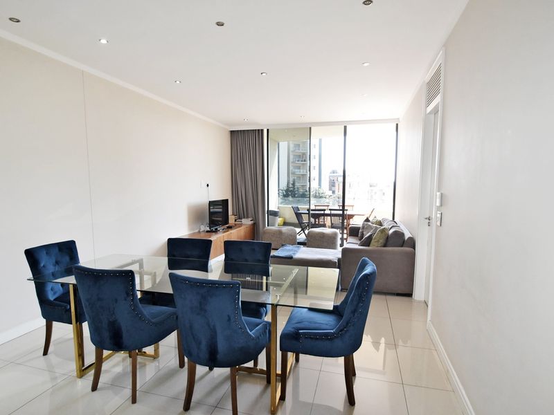 Spacious open-plan living and dining area featuring sleek tiled flooring, recessed lighting, and large sliding glass doors leading to a private balcony.