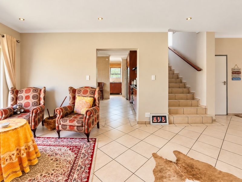 Open plan living area featuring tiled flooring, recessed lighting, and a staircase leading to the upper level, with an adjacent kitchen visible.