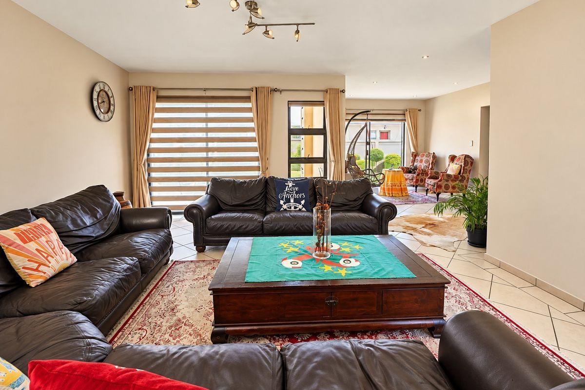 Spacious open-plan living area featuring tiled flooring, modern track lighting, and large windows with blinds, providing ample natural light.