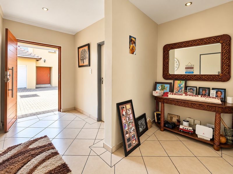 Welcoming entrance hall featuring tiled flooring, recessed downlighting, and a solid wood front door leading to the exterior driveway area.