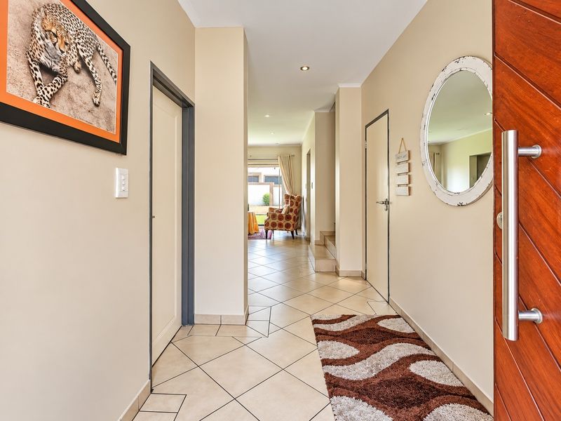 A bright and welcoming entrance hallway featuring tiled flooring, recessed lighting, and a solid wood front door leading into the main living area.