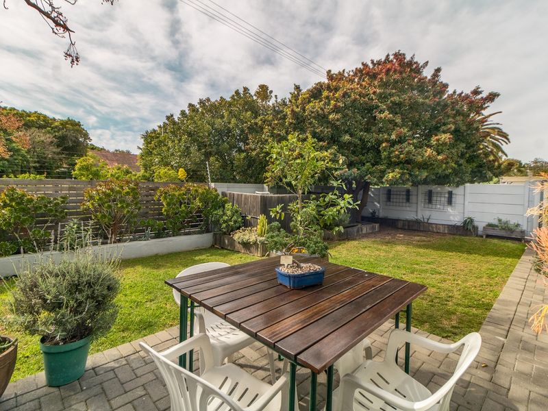 A private rear garden featuring a paved patio area, established lawn, and timber fencing, providing a pleasant outdoor space for relaxation.