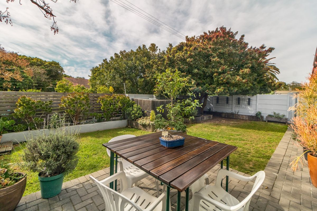 A private rear garden featuring a paved patio area, established lawn, and timber fencing, providing a pleasant outdoor space for relaxation.