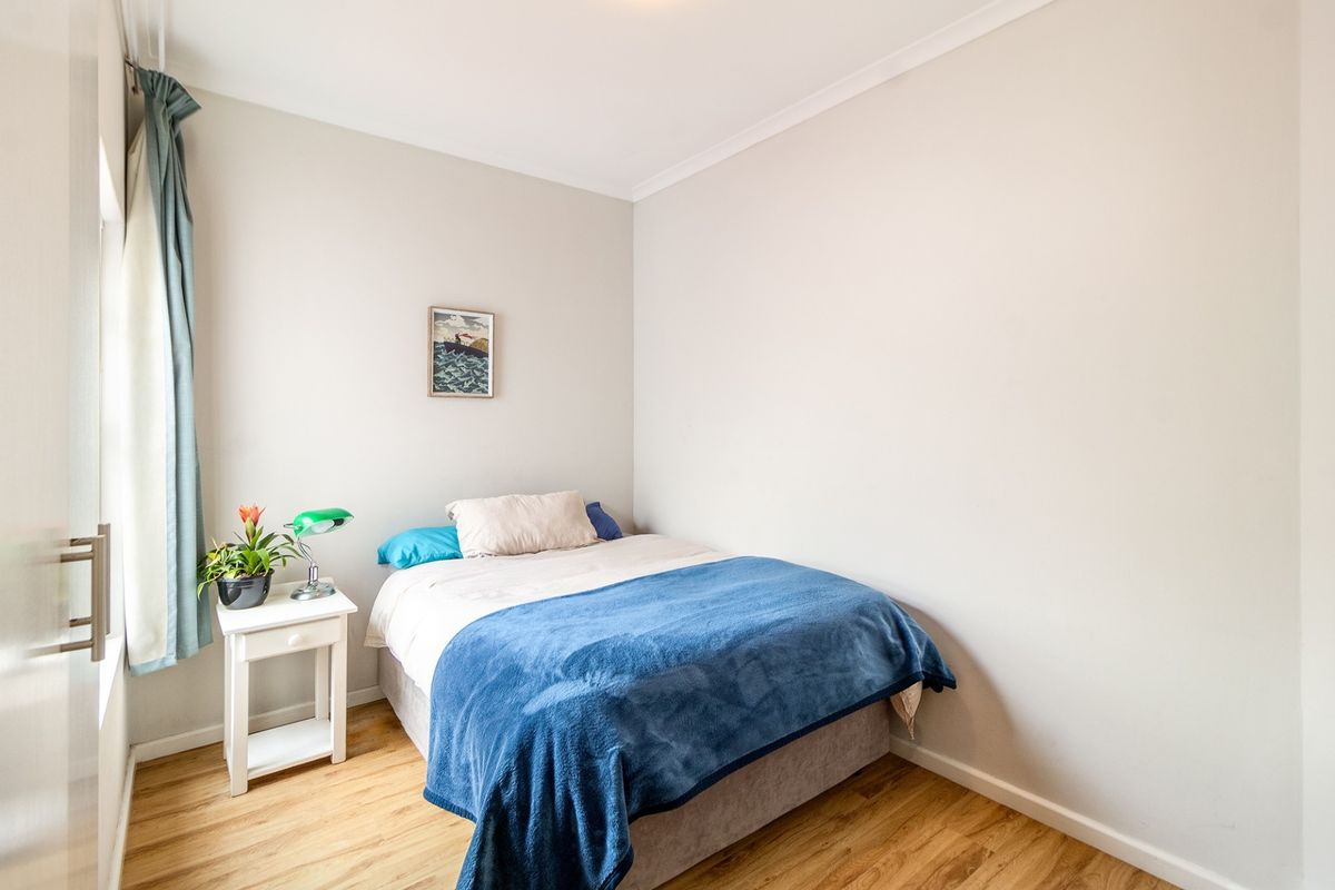 A well-maintained bedroom featuring light-toned laminate flooring and neutral wall finishes, providing a clean and comfortable living space.