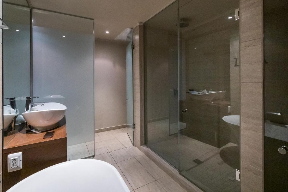 Modern bathroom featuring a glass-enclosed shower, vessel sink with wall-mounted faucet, and neutral tiled finishes.
