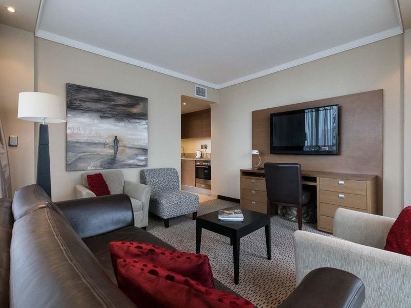 Open plan living area featuring a kitchenette with built-in appliances, a dedicated workspace, and comfortable seating area with neutral finishes.