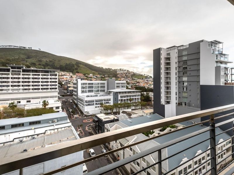 An elevated urban view from a balcony overlooking the surrounding city buildings and hillside landscape.