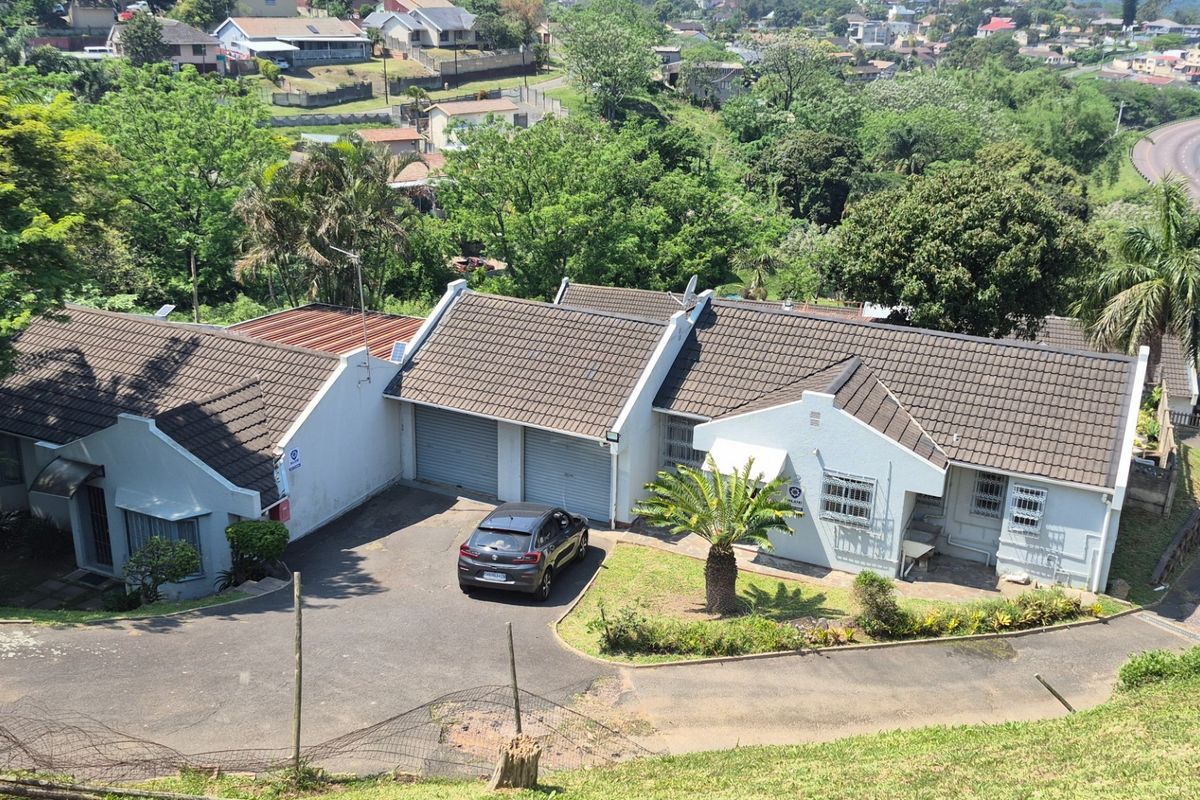 Aerial view of a residential property featuring a tiled roof, double garage, and paved driveway, set within a suburban landscape.