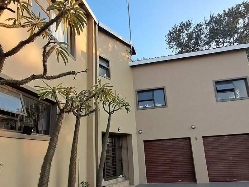Front elevation of a modern double-storey house featuring a double garage with roller shutter doors and aluminium window frames.