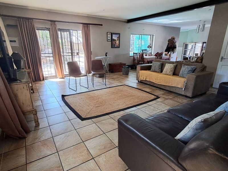 Spacious open-plan living area featuring tiled flooring, exposed brick accents, and large sliding glass doors providing natural light and access to the exterior.