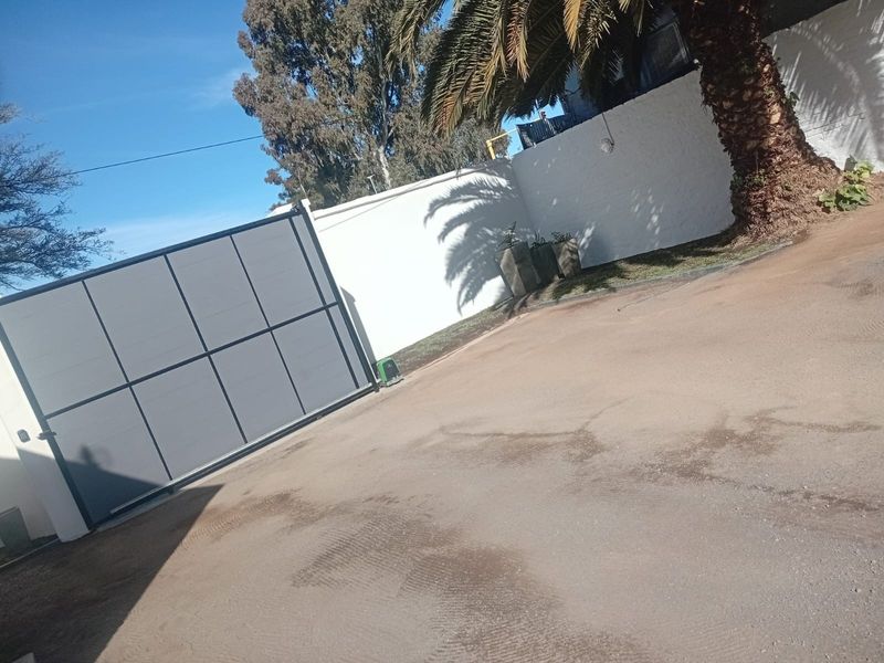 A view of the property entrance featuring a modern sliding gate and a secure perimeter wall.