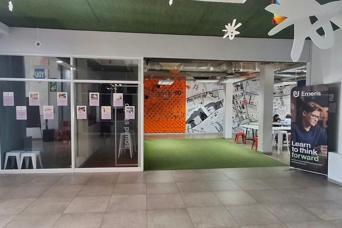 Modern open-plan office space featuring tiled flooring, glass partitions, and an exposed ceiling design, creating a collaborative and contemporary work environment.