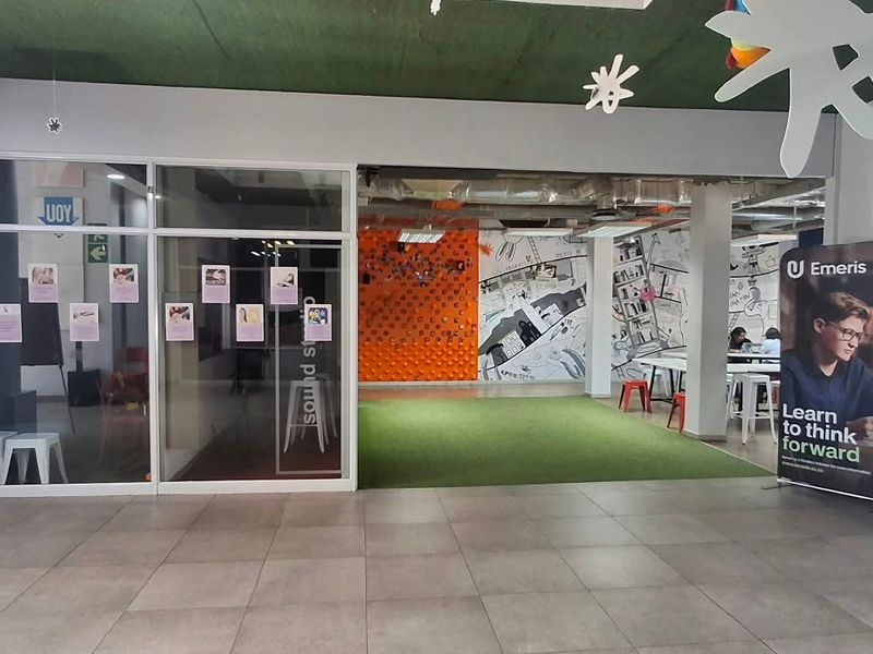Modern open-plan office space featuring tiled flooring, glass partitions, and an exposed ceiling design, creating a collaborative and contemporary work environment.