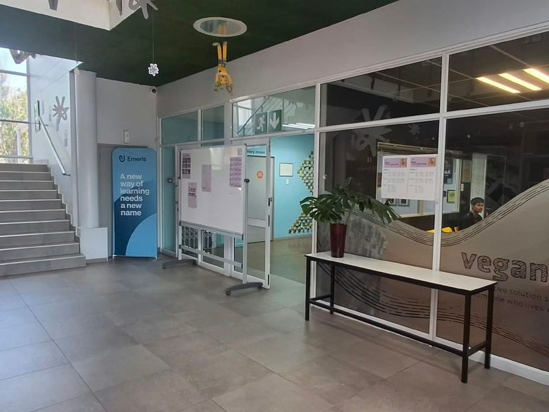 Spacious office building entrance lobby featuring tiled flooring, a staircase, and glass-partitioned office spaces with modern finishes.
