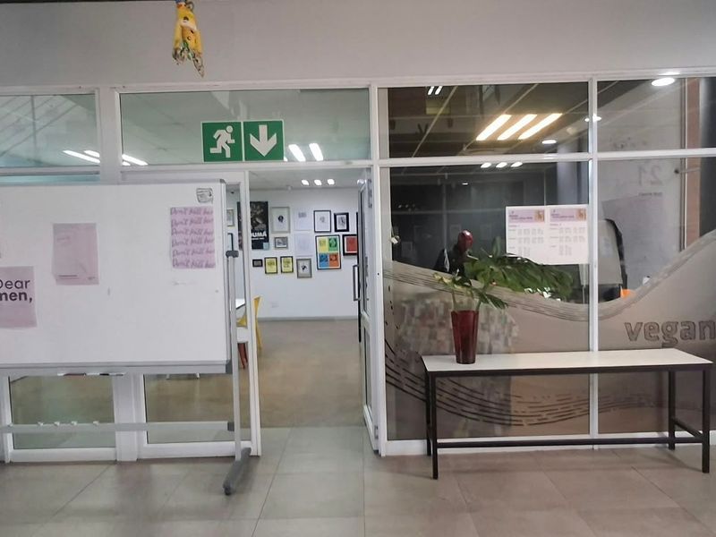 Office interior featuring glass partition walls, tiled flooring, and recessed lighting, providing a functional and professional workspace environment.