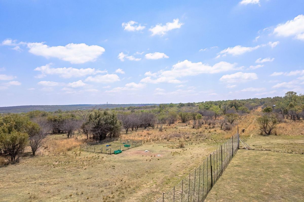 An aerial view of the expansive farm property featuring open grazing land and perimeter fencing under a clear sky.