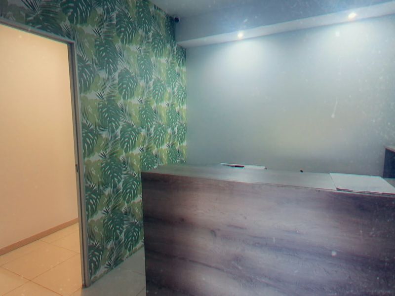 A commercial entry area featuring a built-in reception desk, patterned wallpaper, and recessed downlighting, presenting a clean and professional space.