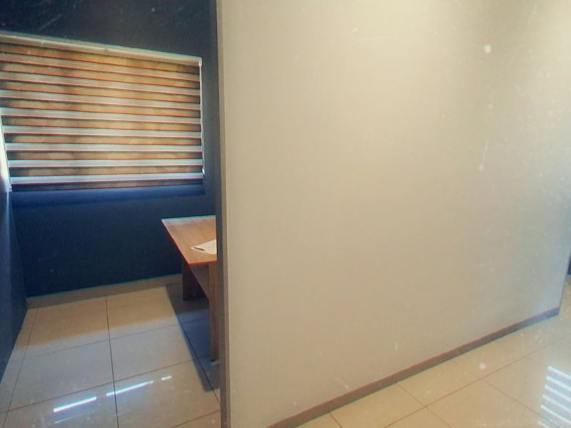 A clean, modern office space featuring tiled flooring and zebra blinds, providing a bright and professional environment suitable for various commercial uses.