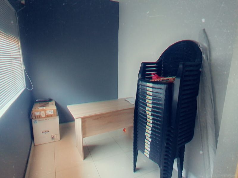 A small office space featuring tiled flooring and venetian blinds, currently used for storage.